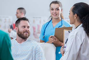 man in hospital gown talking to his SSM Health physican